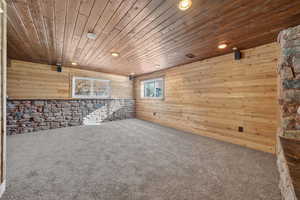 Carpeted spare room featuring wood ceiling, wood walls, and recessed lighting