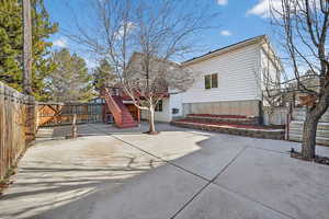 Rear view of house featuring a fenced backyard, stairway, and a patio area