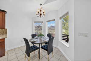 Dining area featuring light tile  floors, a chandelier, and vaulted ceiling