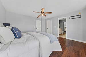 Bedroom featuring dark wood-type flooring, ceiling fan, and connected ensuite
