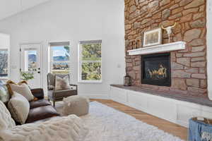 Living area with a fireplace, light wood-type flooring, and high vaulted ceiling