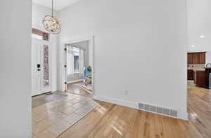 Foyer entrance featuring light wood-style flooring, a towering ceiling, and a chandelier