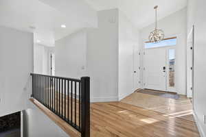 Entrance foyer featuring light wood-style floors, a chandelier, and high vaulted ceiling
