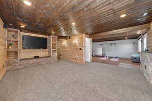 living room with wooden ceiling, recessed lighting, carpet, and wood walls. Built in entertainment center