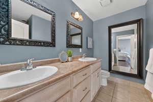 Ensuite bathroom with double vanity, light tile  flooring, and a textured ceiling