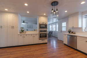 Kitchen featuring white cabinets, appliances with stainless steel finishes, light countertops, recessed lighting, and a textured ceiling