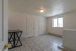 Laundry area with washer / clothes dryer, a textured ceiling, and a baseboard heating unit