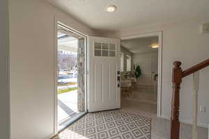 Foyer featuring a textured ceiling, light tile patterned floors, and stairway