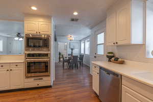 Kitchen featuring a textured ceiling, appliances with stainless steel finishes, light countertops, dark wood finished floors, and recessed lighting
