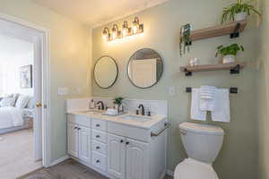 Ensuite bathroom featuring double vanity, a textured ceiling, and wood finished floors