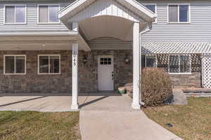 Property entrance featuring covered porch, stone siding, and a lawn