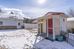 Snow covered structure with a storage shed and a gate