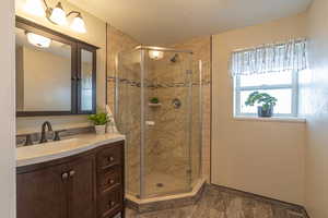 Bathroom featuring vanity, a shower stall, and a textured ceiling