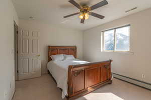 Bedroom featuring a baseboard heating unit, a textured ceiling, light carpet, and ceiling fan