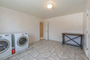 Laundry room featuring a textured ceiling and washer and clothes dryer