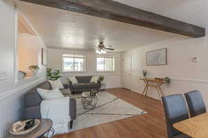 Living area featuring a textured ceiling, wainscoting, wood finished floors, and ceiling fan