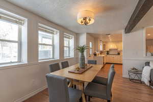 Dining space with a textured ceiling, dark wood-style flooring, beam ceiling, and recessed lighting
