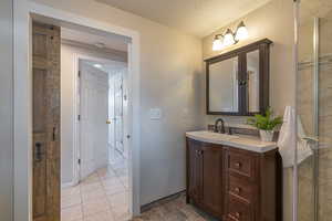 Full bath with a textured ceiling, vanity, and a stall shower