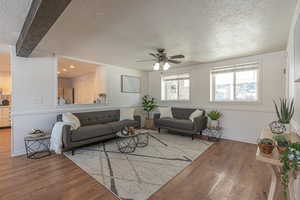 Living room featuring a wainscoted wall, a textured ceiling, ceiling fan, and hardwood / wood-style floors