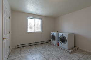 Washroom featuring a baseboard heating unit, washing machine and clothes dryer, and a textured ceiling
