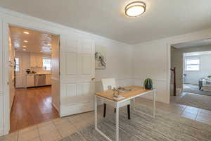 Office area with a textured ceiling, light tile patterned flooring, plenty of natural light, and crown molding