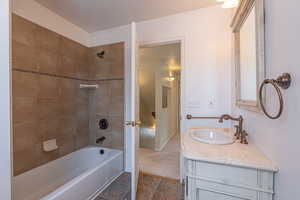 Full bathroom with tub / shower combination, vanity, and a textured ceiling
