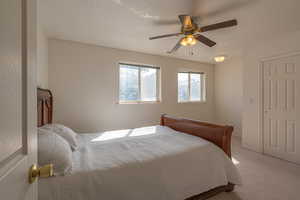 Carpeted bedroom featuring a textured ceiling and a ceiling fan