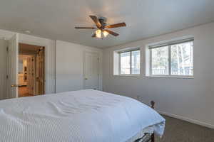 Carpeted bedroom with a textured ceiling and ceiling fan