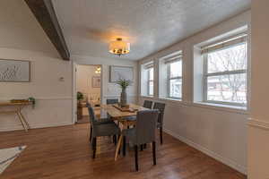 Dining area featuring hardwood / wood-style flooring, wainscoting, and a textured ceiling