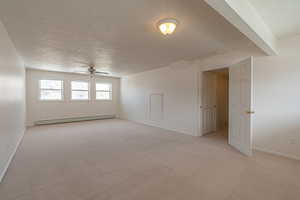 Unfurnished room with a textured ceiling, a baseboard heating unit, light carpet, and a ceiling fan