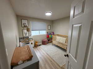 Bedroom featuring a nursery area and light wood finished floors