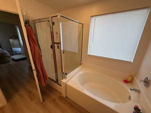 Bathroom with a garden tub, a stall shower, wood finished floors, and connected bathroom