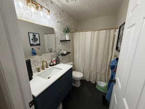 Bathroom with vanity, a shower with shower curtain, a textured ceiling, and wallpapered walls
