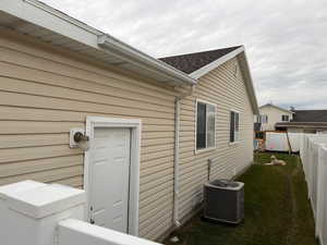 View of side of home with a fenced backyard and a central AC unit