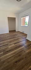 East unit Bedroom 1 with a textured ceiling, dark wood-type flooring, and a closet