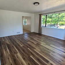 East living room featuring a textured ceiling and dark wood-style flooring