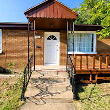 Entrance to east unit featuring brick siding and a deck
