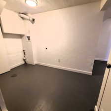 West unit laundry room with a textured wall, a textured ceiling, finished concrete floors, and hookup for a washing machine