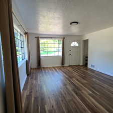 East living room with a textured ceiling and dark wood-style floors