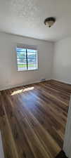 East unit Bedroom 2 Unfurnished room with a textured ceiling and dark wood-type flooring