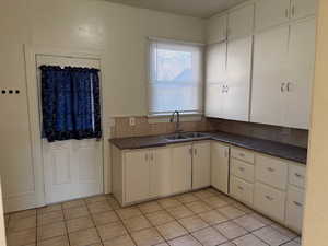 Kitchen featuring dark countertops, light tile patterned flooring, and white cabinetry