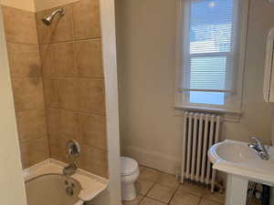 Bathroom with radiator heating unit, shower / bathtub combination, and tile patterned floors