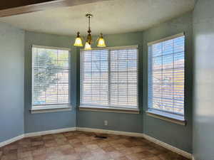 Unfurnished dining area with a chandelier and a textured ceiling