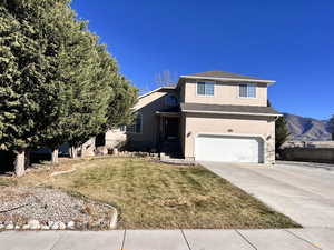 View of front of property with stucco siding, a front yard, driveway, an attached garage, and a shingled roof