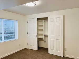 Unfurnished bedroom featuring dark carpet and a closet