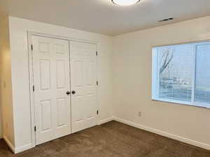 Unfurnished bedroom featuring dark carpet and a closet