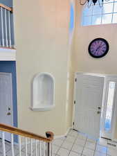 Entrance foyer with light tile patterned floors, stairs, and a chandelier