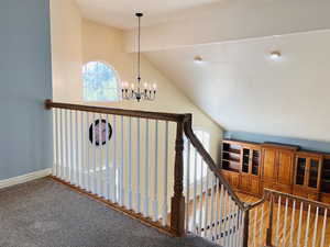 Staircase with healthy amount of natural light, carpet flooring, and a chandelier