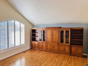 Unfurnished living room featuring light wood-style floors and vaulted ceiling