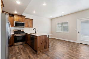 Kitchen with a peninsula, stainless steel appliances, dark wood-style floors, recessed lighting, and a textured ceiling
